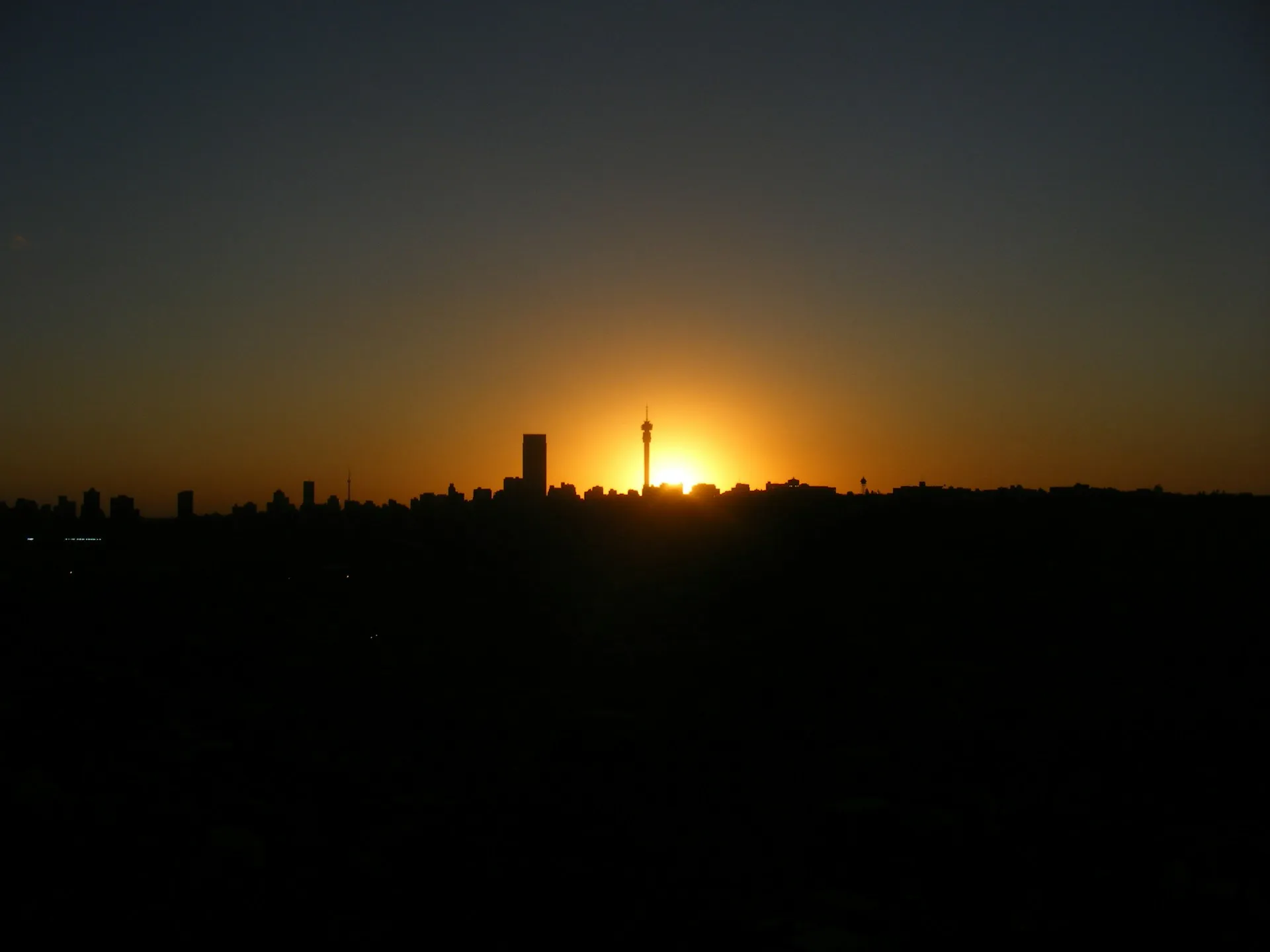 Johannesburg city skyline silhouetted against the setting sun.